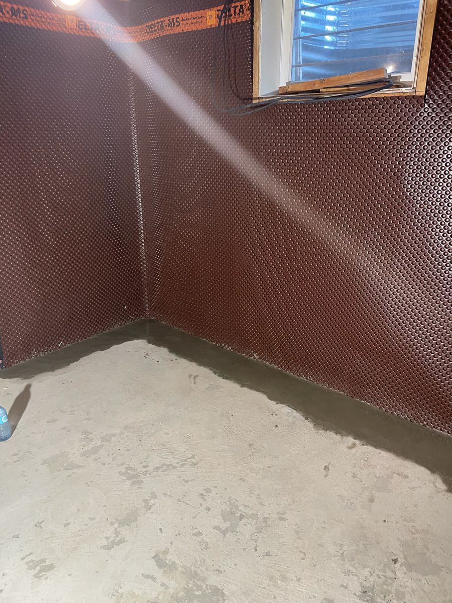 Delta membrane finished into a basement corner with new concrete at the floor