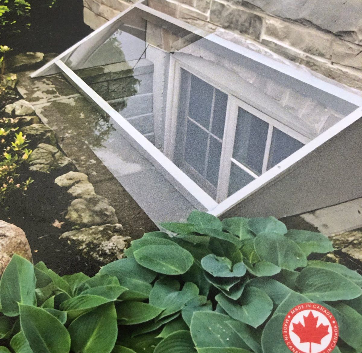 Clear custom window well cover over a basement window on a stone house