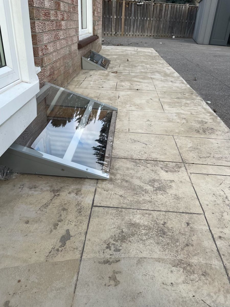 Window well cover beside a stone walkway